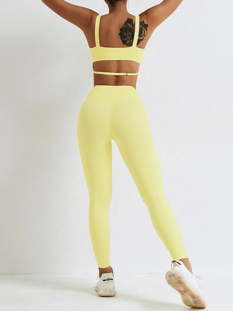 Woman wearing yellow seamless gym sports suit with leggings and strappy bra, perfect for yoga and fitness. Nylon spandex blend.